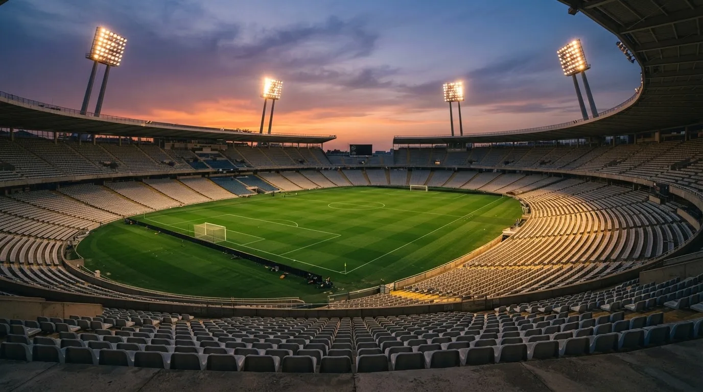 Un estadio de fútbol vacío con torres de iluminación al atardecer