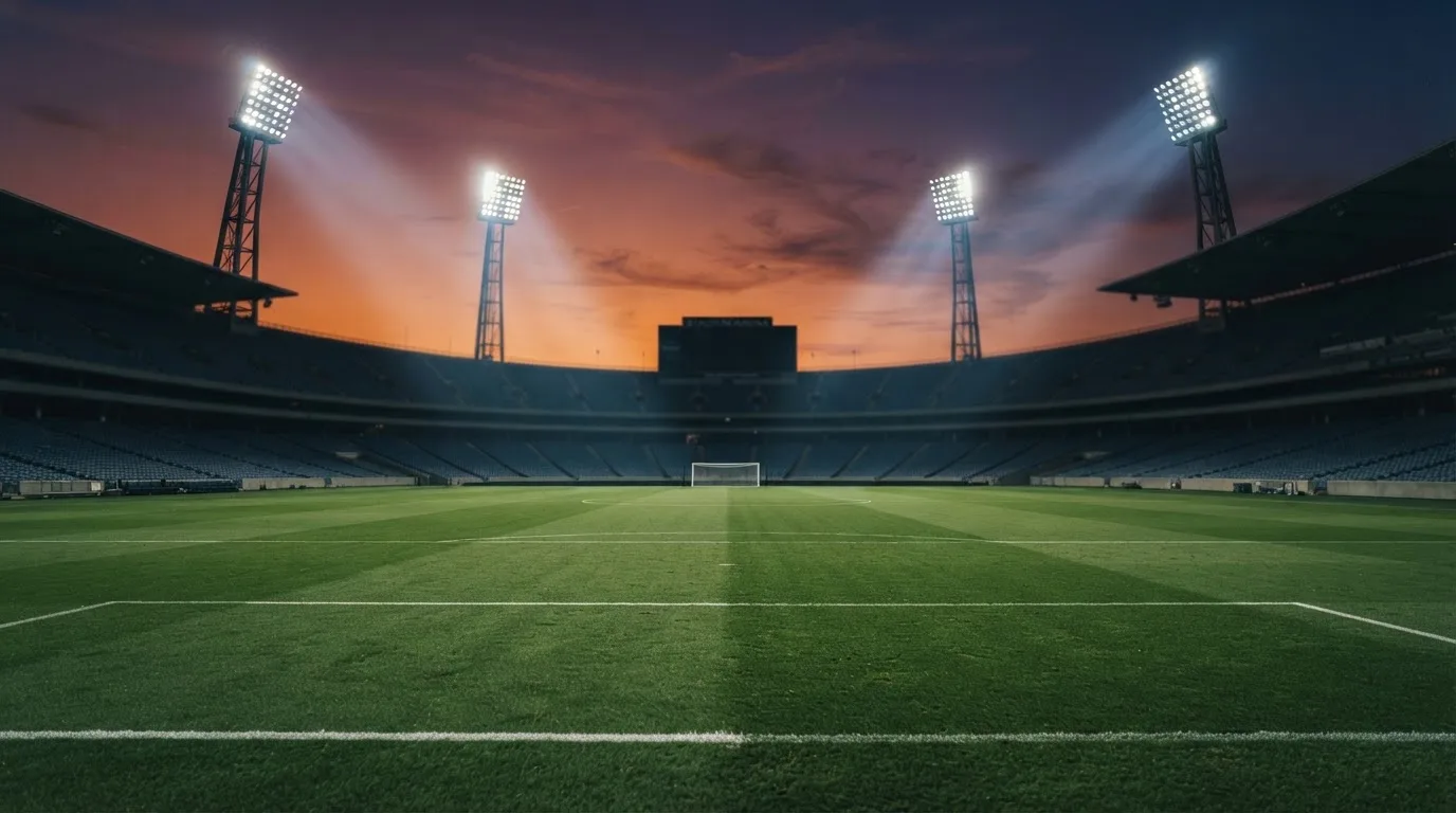 Un estadio de fútbol vacío con torres de iluminación al atardecer