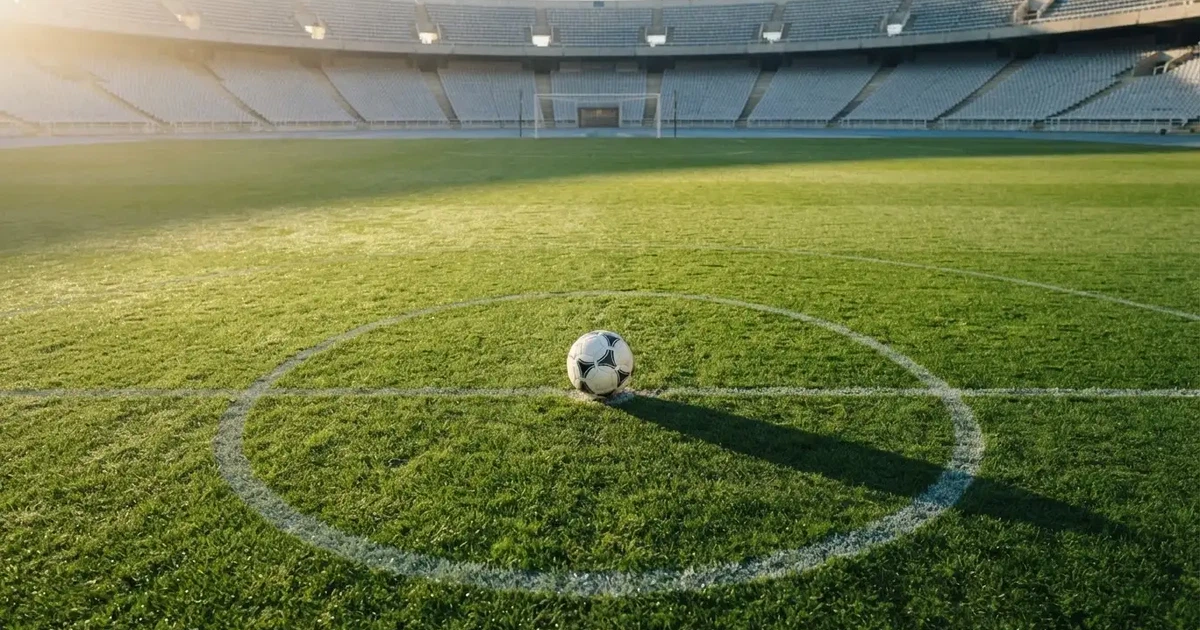 Un balón en el punto central de un campo de césped a la luz de la mañana