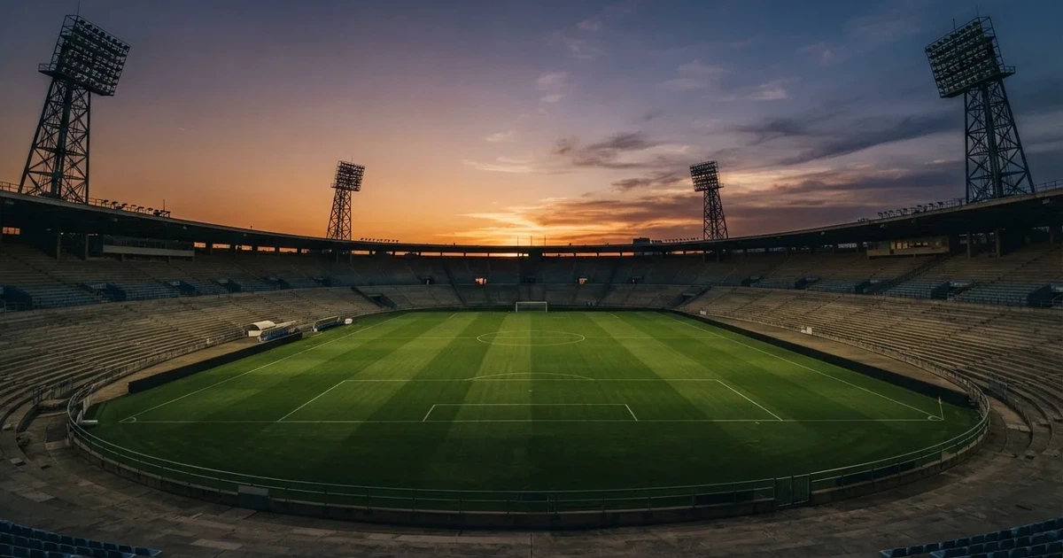 Un estadio de fútbol vacío con torres de iluminación al atardecer