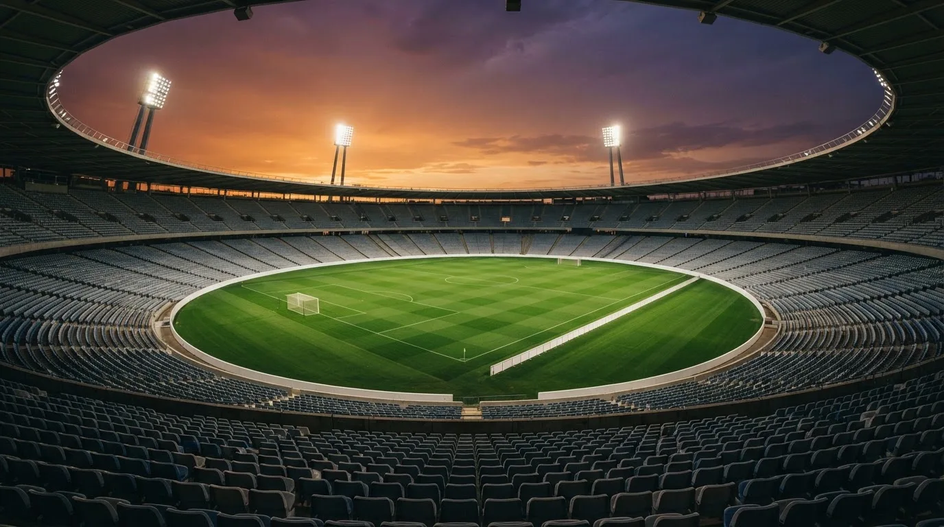 Un estadio de fútbol vacío con torres de iluminación al atardecer