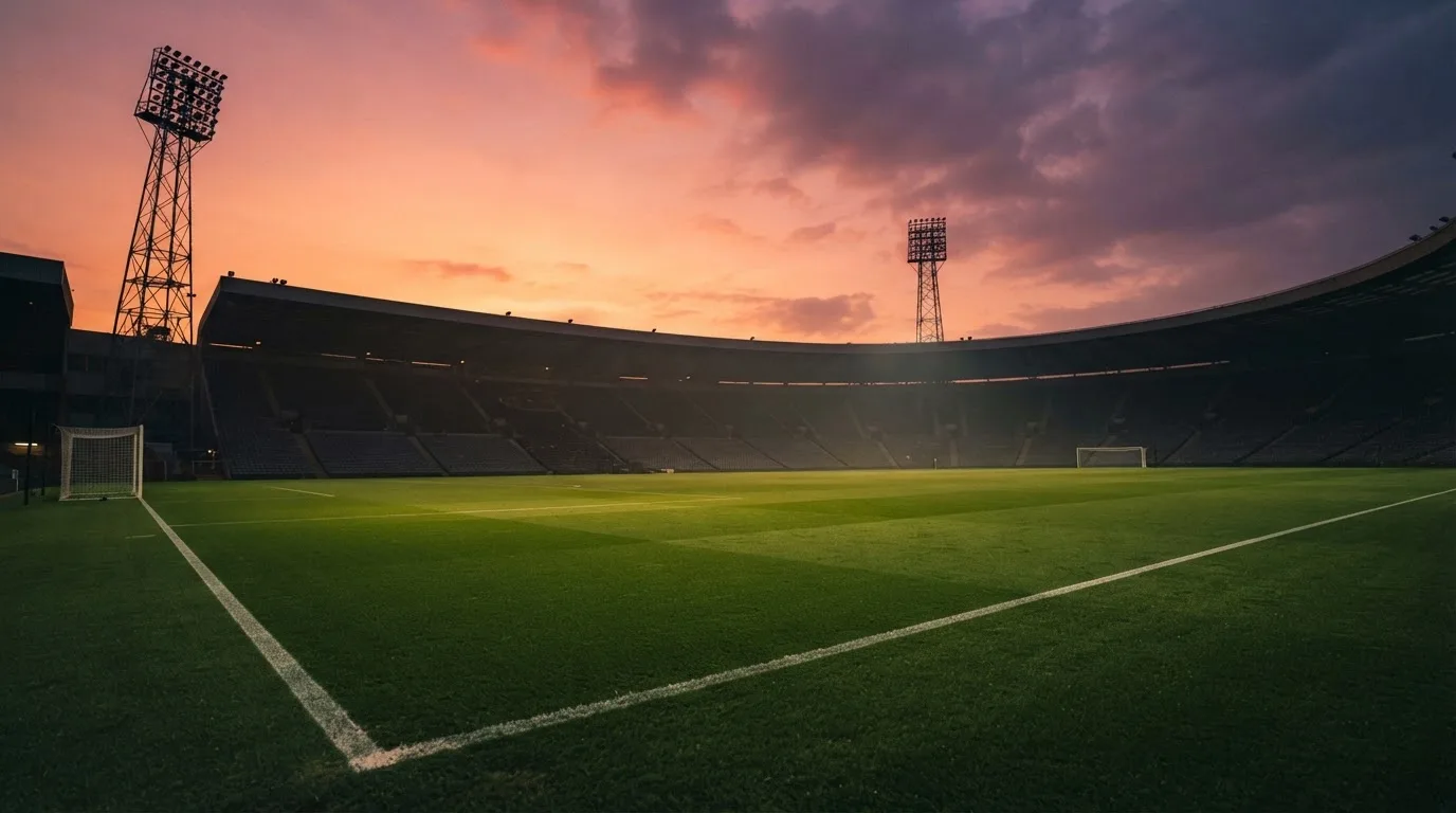Un estadio de fútbol vacío con torres de iluminación al atardecer