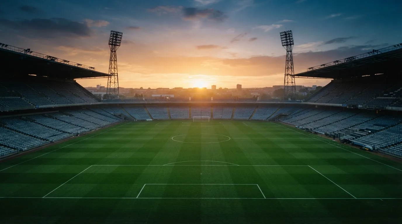 Un estadio de fútbol vacío con torres de iluminación al atardecer