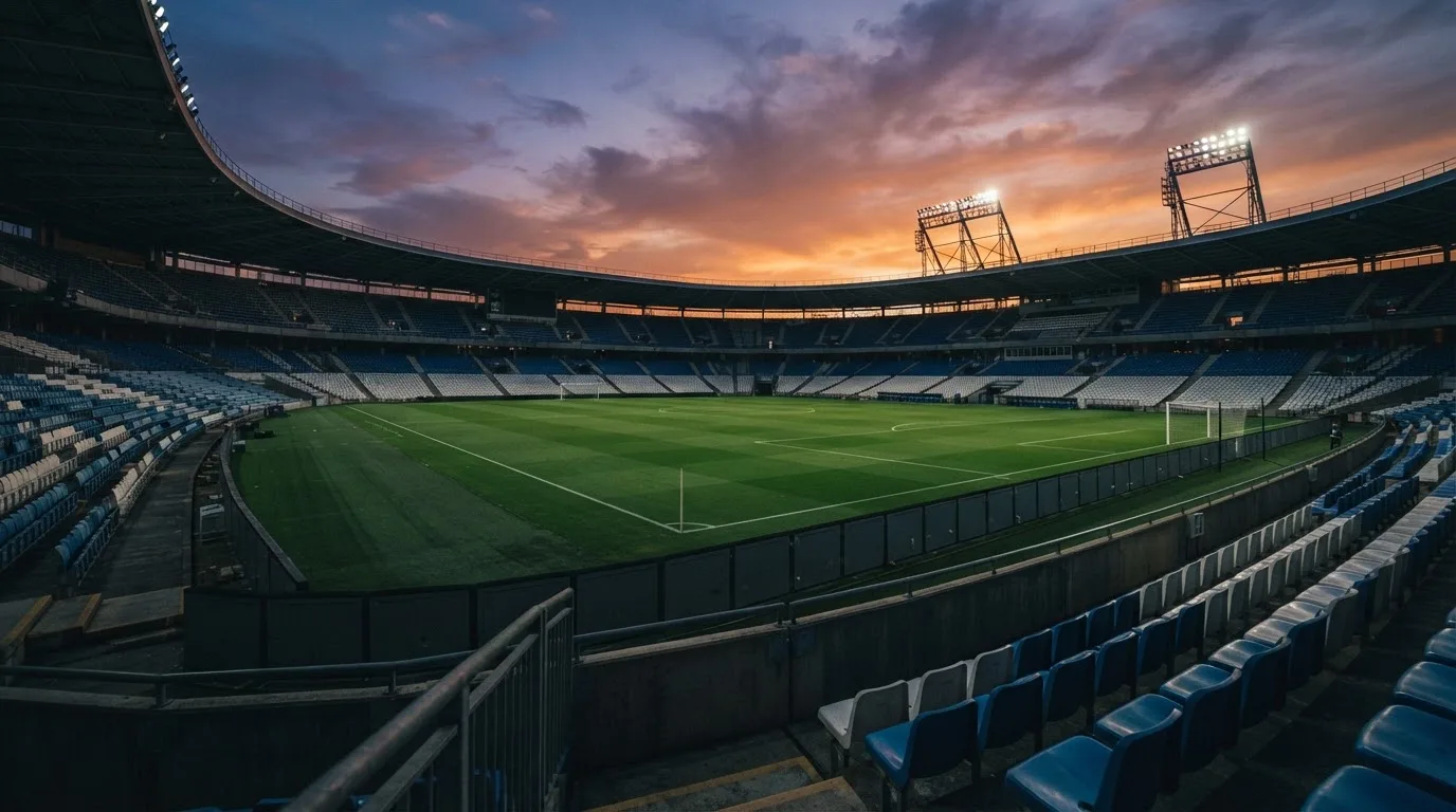 Un estadio de fútbol vacío con torres de iluminación al atardecer