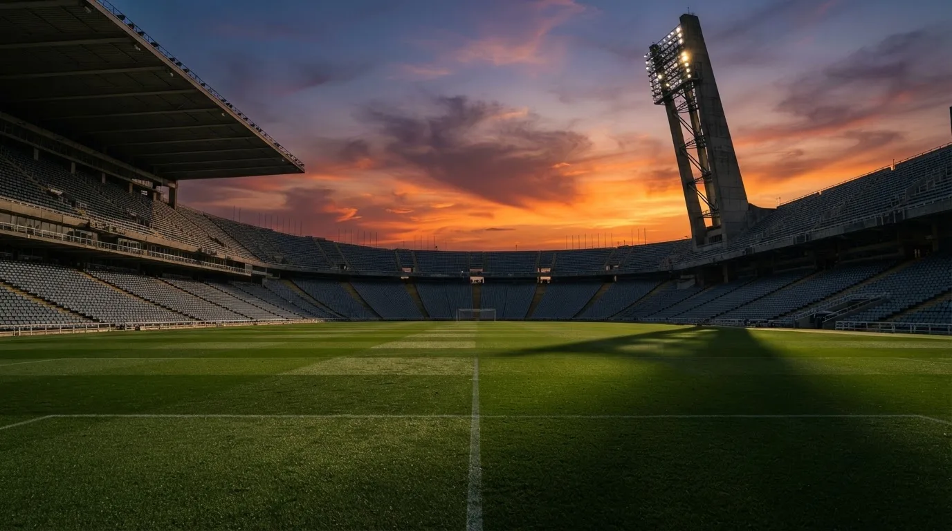 Un estadio de fútbol vacío con torres de iluminación al atardecer