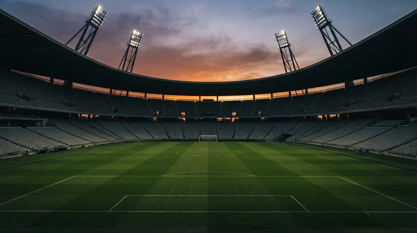 Un estadio de fútbol vacío con torres de iluminación al atardecer