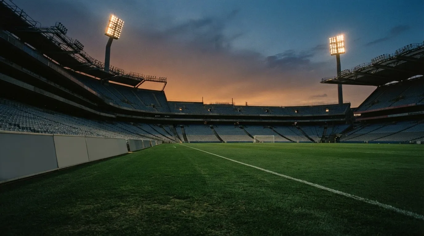 Un estadio de fútbol vacío con torres de iluminación al atardecer