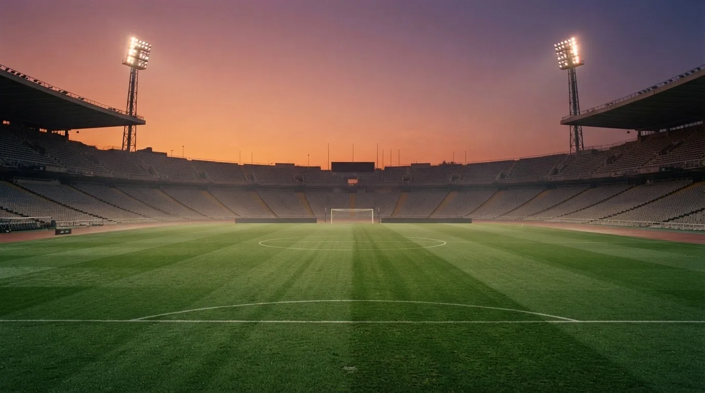 Un estadio de fútbol vacío con torres de iluminación al atardecer