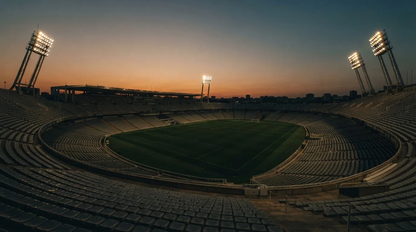 Un estadio de fútbol vacío con torres de iluminación al atardecer