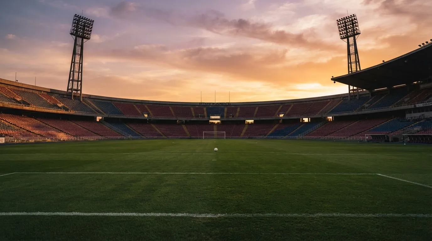 Un estadio de fútbol vacío con torres de iluminación al atardecer