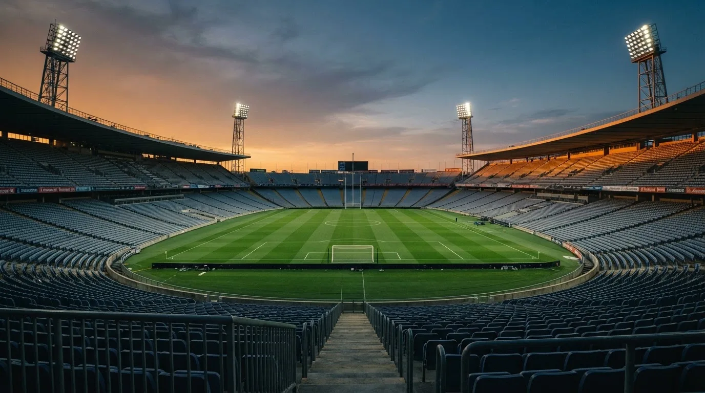 Un estadio de fútbol vacío con torres de iluminación al atardecer